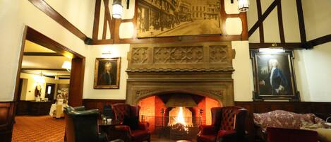 A traditional lobby with a fireplace, seating area, and a large mural on the wall.