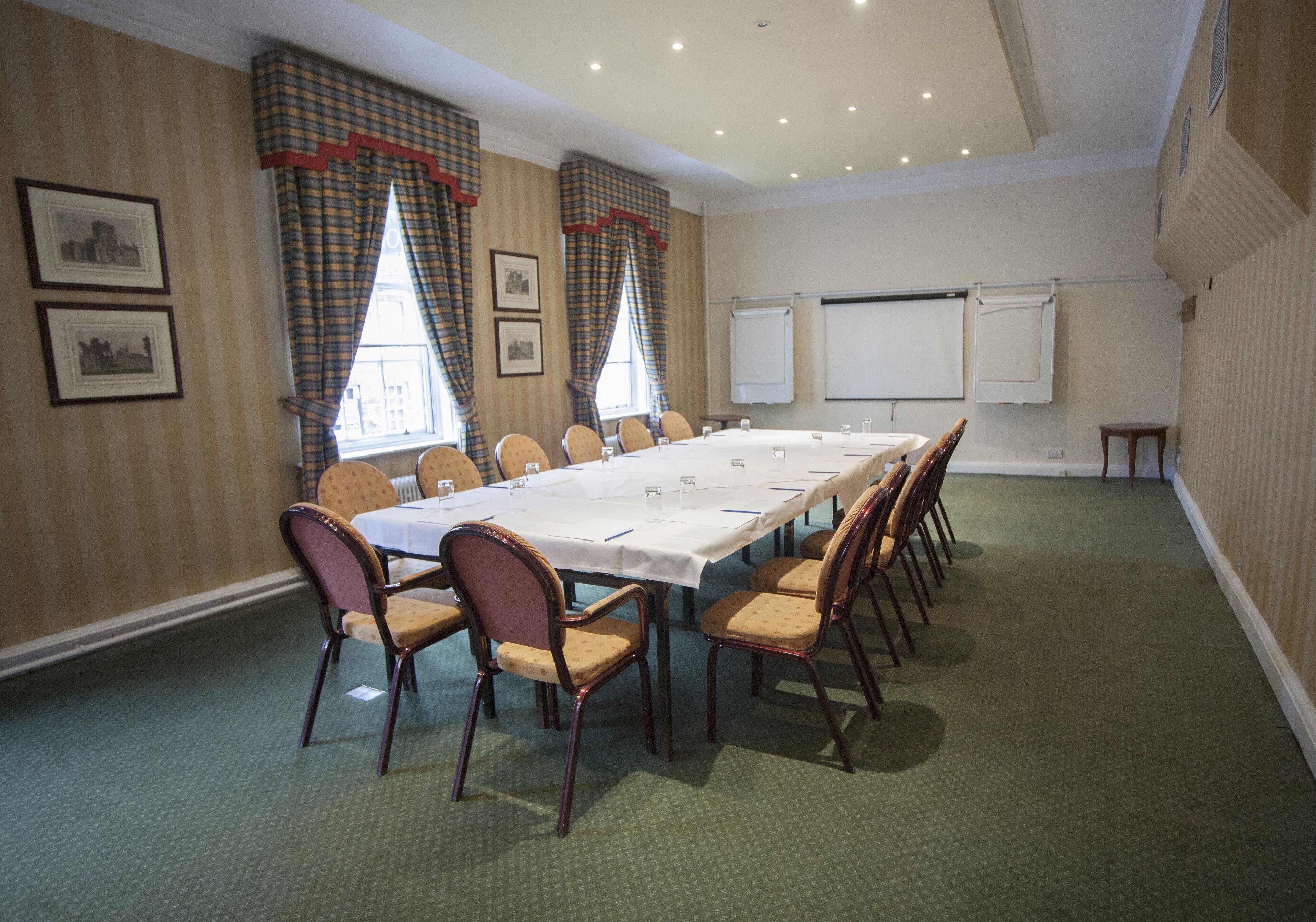 A conference room with a long table, chairs, a projector screen, and a whiteboard.