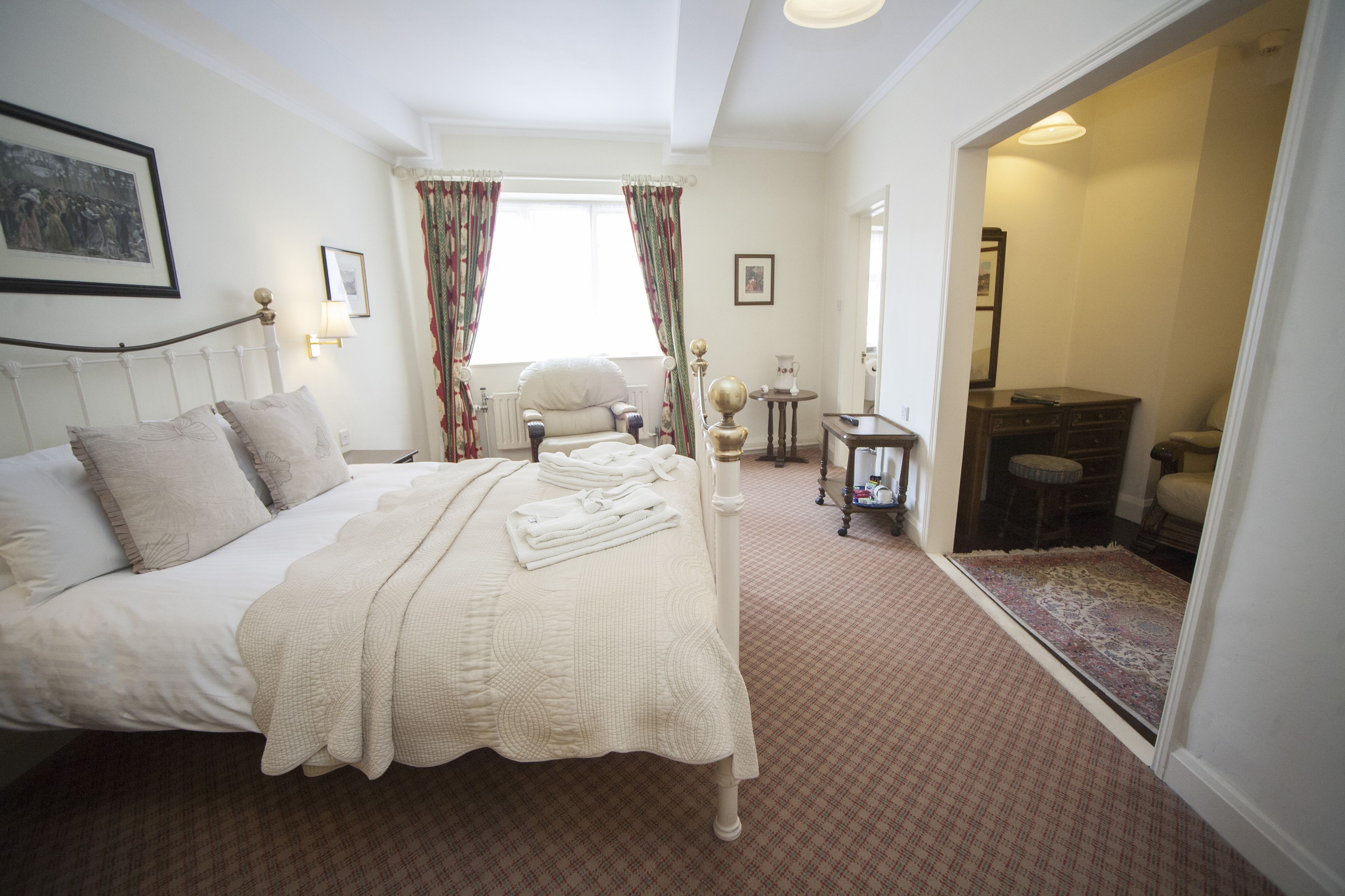 Une chambre à coucher avec un lit, une chaise, une petite table et un miroir.