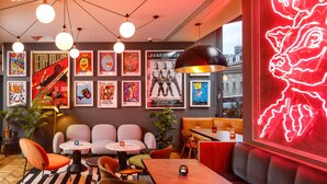 A modern lounge area with seating, tables, and artwork on the walls. - ibis Styles Edinburgh Centre St Andrew Square (Edinburgh)
