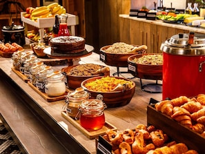 A buffet with various food items, including granola, pastries, and a cake. - ibis Styles Edinburgh Centre St Andrew Square (Edinburgh)