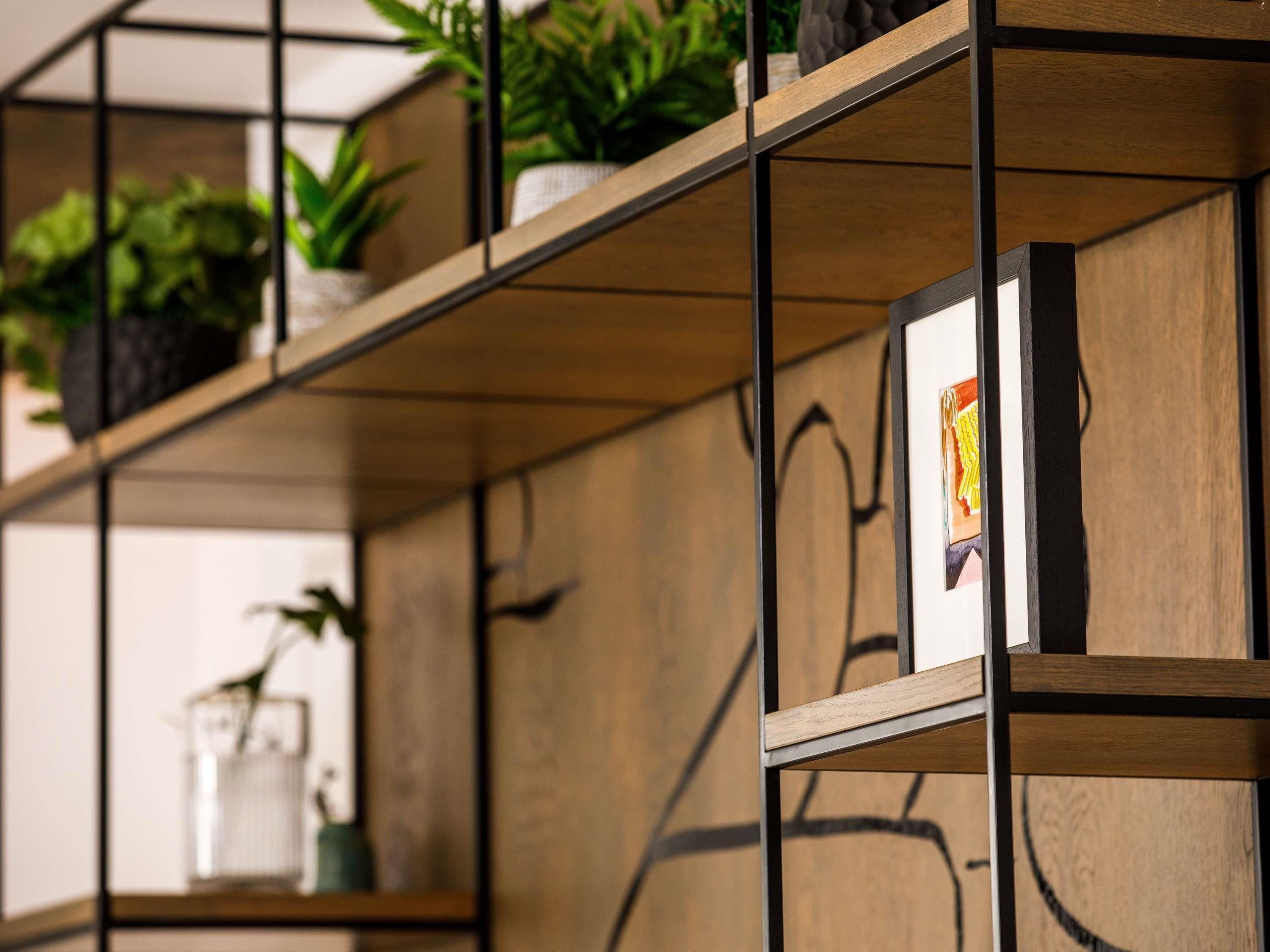 A wooden shelving unit with plants and framed artwork.