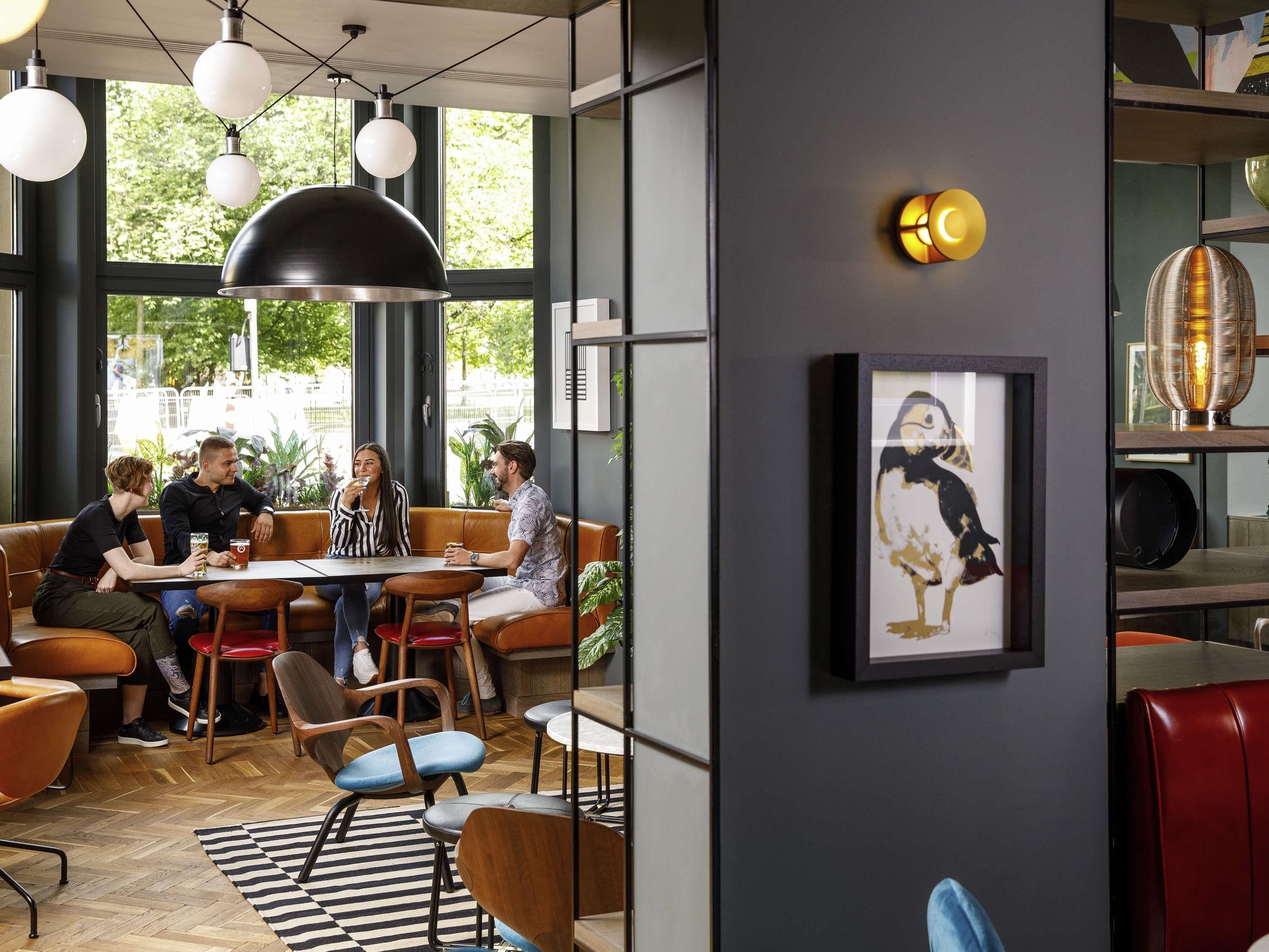 Un café moderno con asientos de cuero, iluminación colgante y una obra de arte enmarcada en la pared.