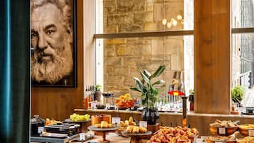 A buffet with various food items and a large painting on the wall.