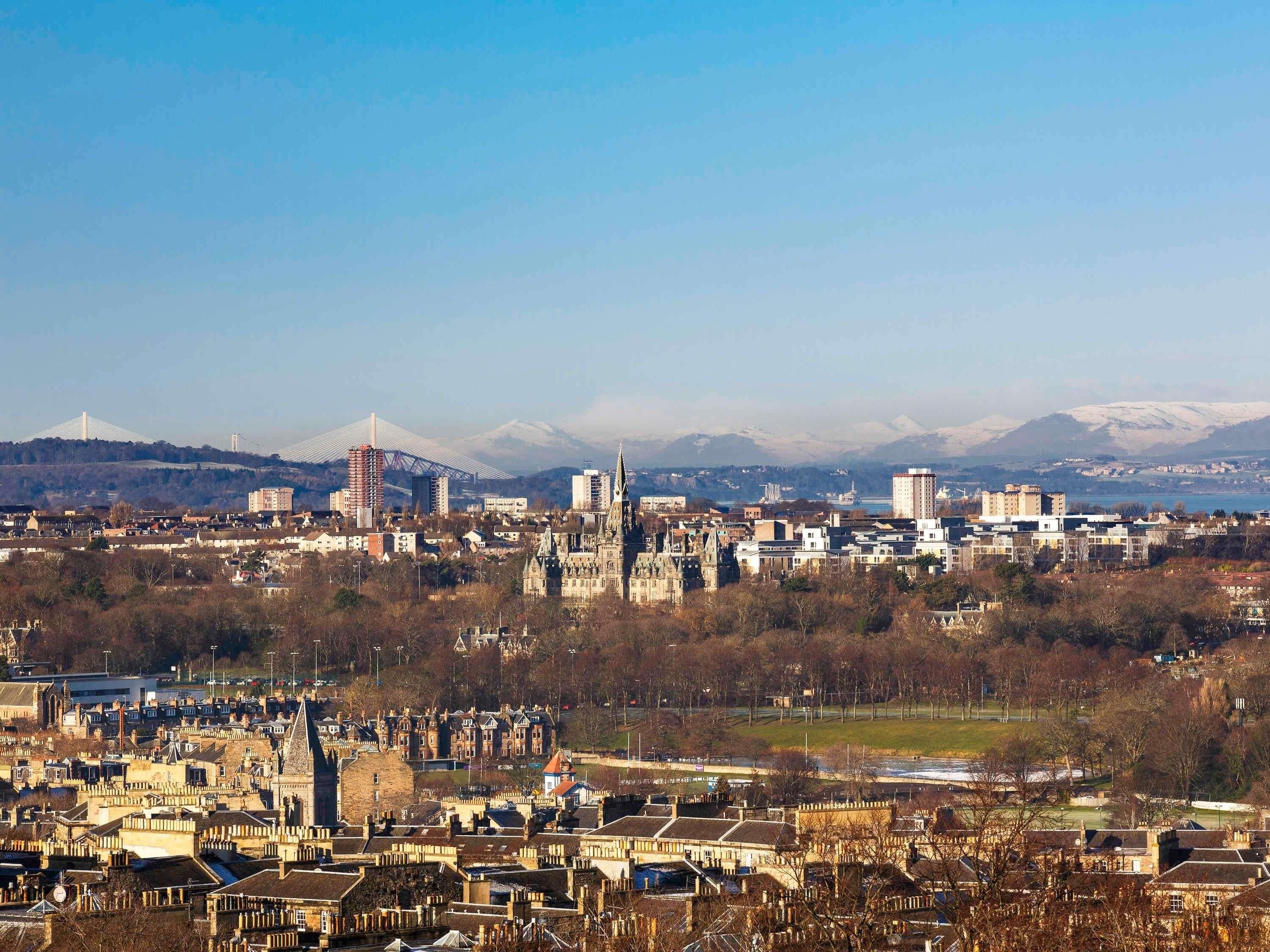 A cityscape with historic buildings, modern architecture, and a distant mountain range.