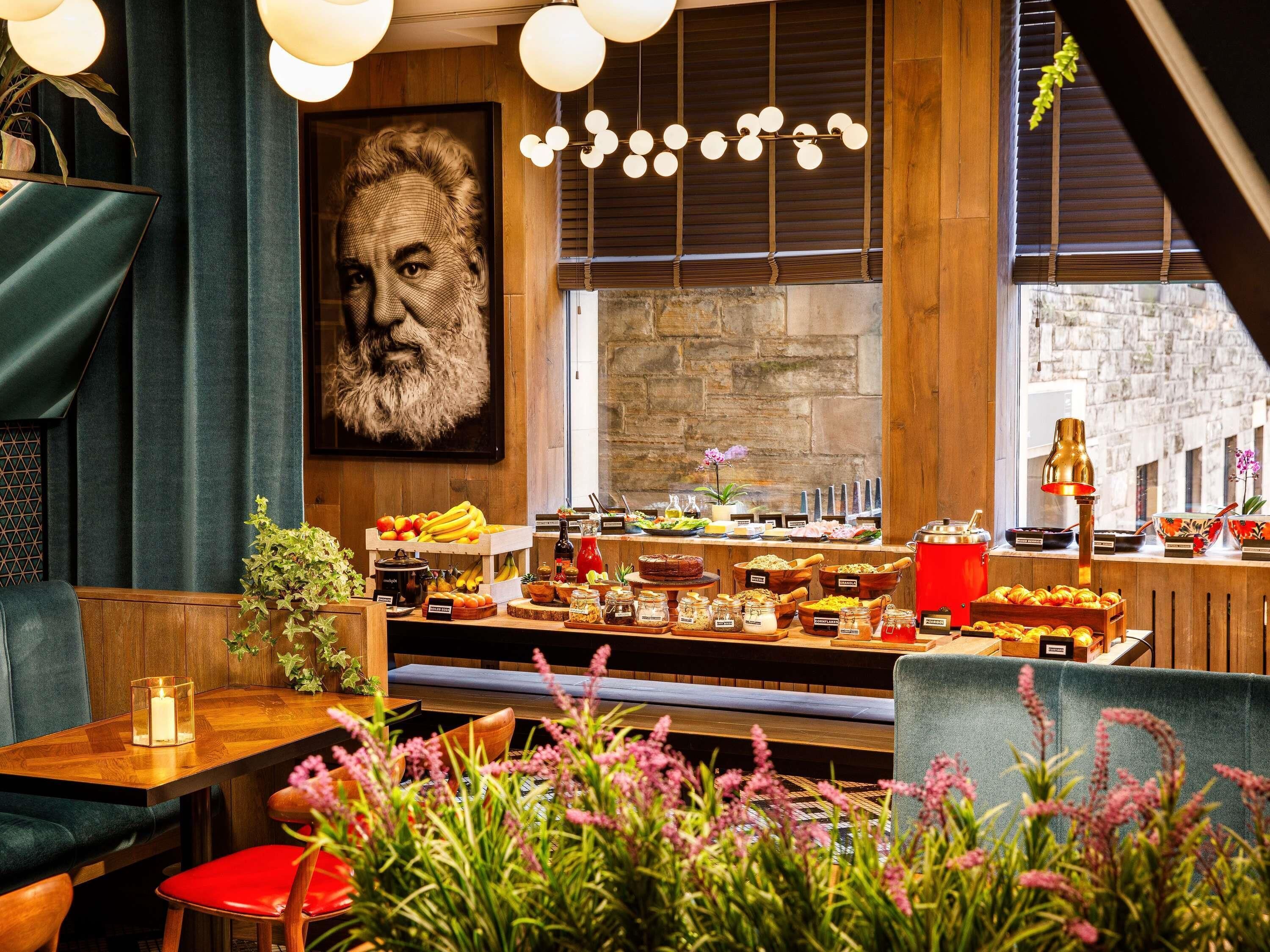 A restaurant interior with a buffet, wooden furniture, and a large portrait on the wall.