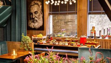A restaurant interior with a buffet, wooden furniture, and a large portrait on the wall.