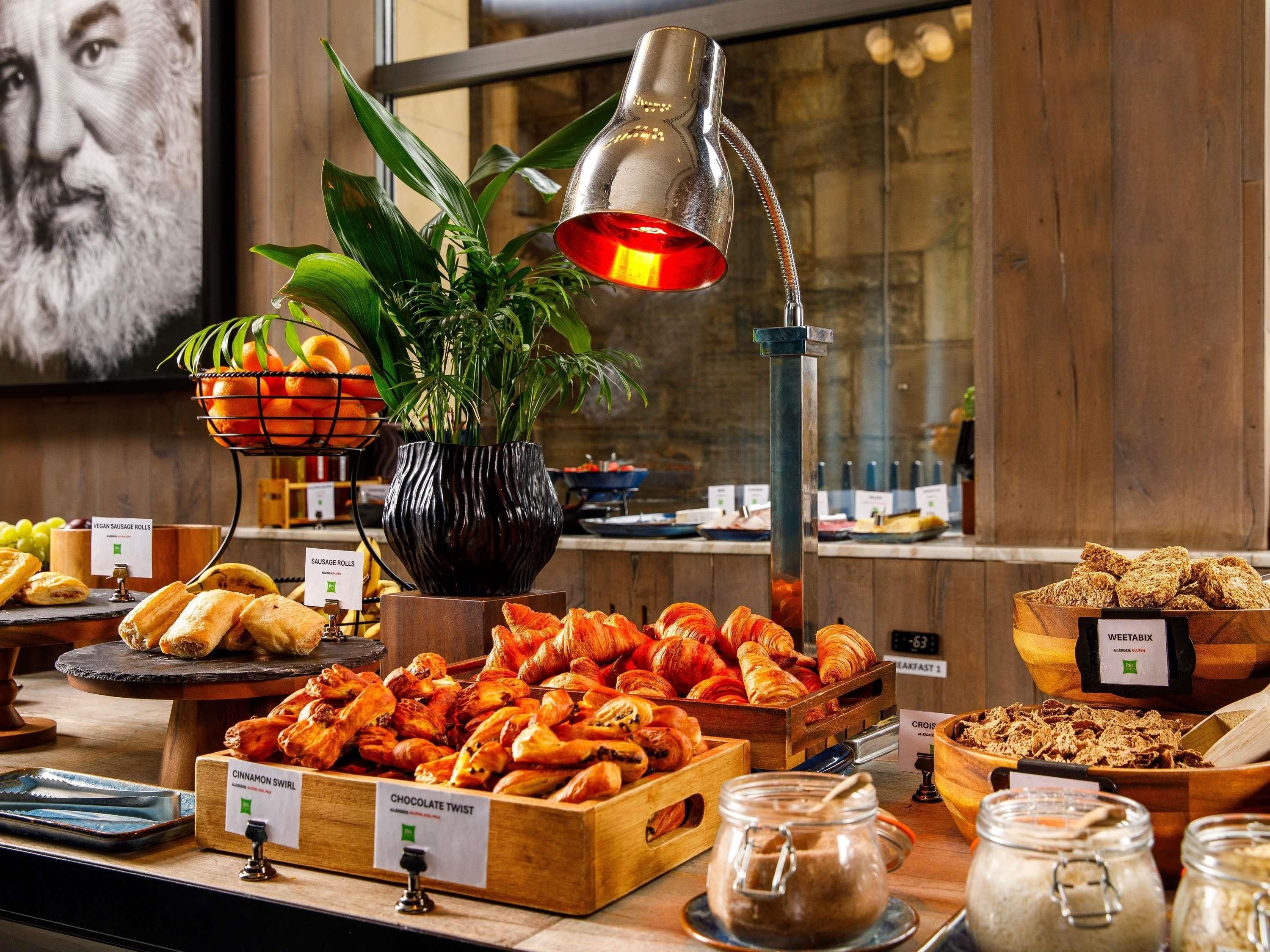 A buffet with various food items including rolls, pastries, and a plant centerpiece.