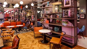 Een modern interieur met houten vloeren, oranje en bruine zittingen, en planken met diverse decoratieve objecten.