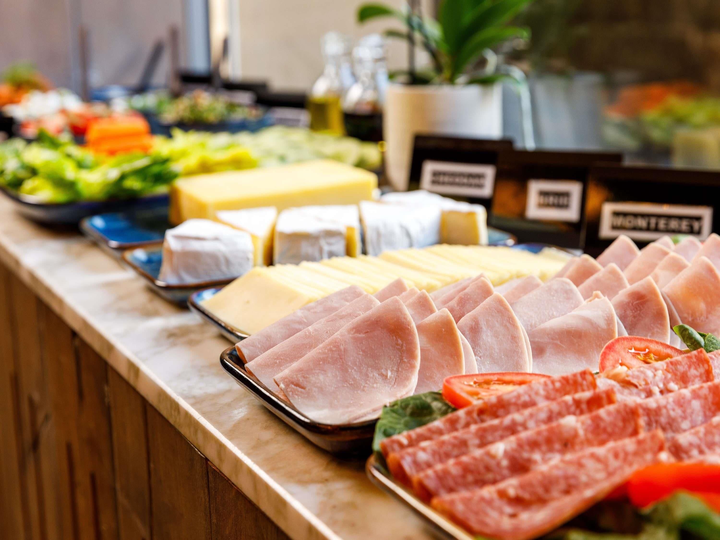 Een buffet met verschillende kazen, vleeswaren en een salade.