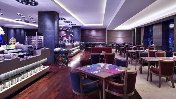 A modern restaurant with wooden flooring, round tables, and chairs. - Grand Mercure Bandung Setiabudi (Bandung)