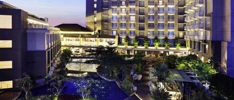 Ein mehrstöckiges Hotel mit Dachterrasse, Innenhof mit Wasserspiel und Außenbereichen zum Sitzen.