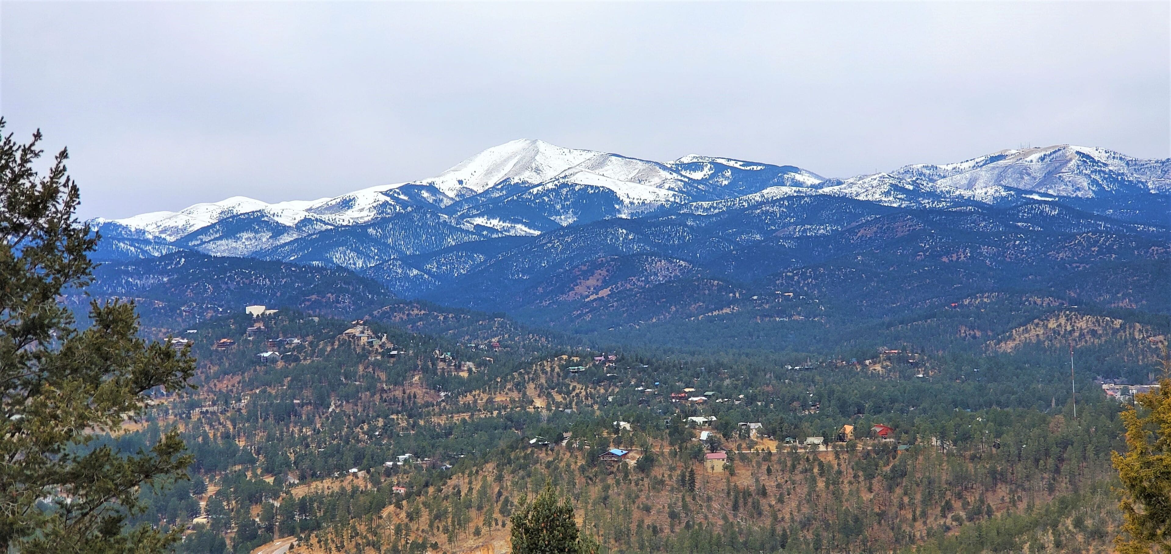 A mountainous landscape with snow-capped peaks and scattered buildings.