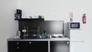 A compact kitchen with a black countertop, a white refrigerator, and a microwave. - Grundarfjördur Hostel (Grundarfjörður)