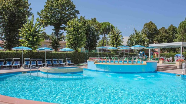 Una piscina con múltiples carriles, sillas de descanso y sombrillas.