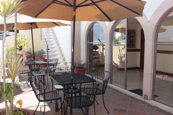 An outdoor patio with a table and chairs, surrounded by potted plants and a large umbrella. - Hotel Qualitel Centro Histórico (Morelia)