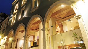 Un immeuble à étages, doté de grandes fenêtres en arc de cercle et d’une façade en verre.