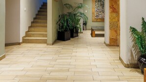 Un hall d’entrée spacieux avec un escalier en bois, des plantes en pot et un mur en pierre.