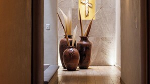 Un couloir avec un mur en marbre, un symbole de croix et deux vases contenant des plantes.