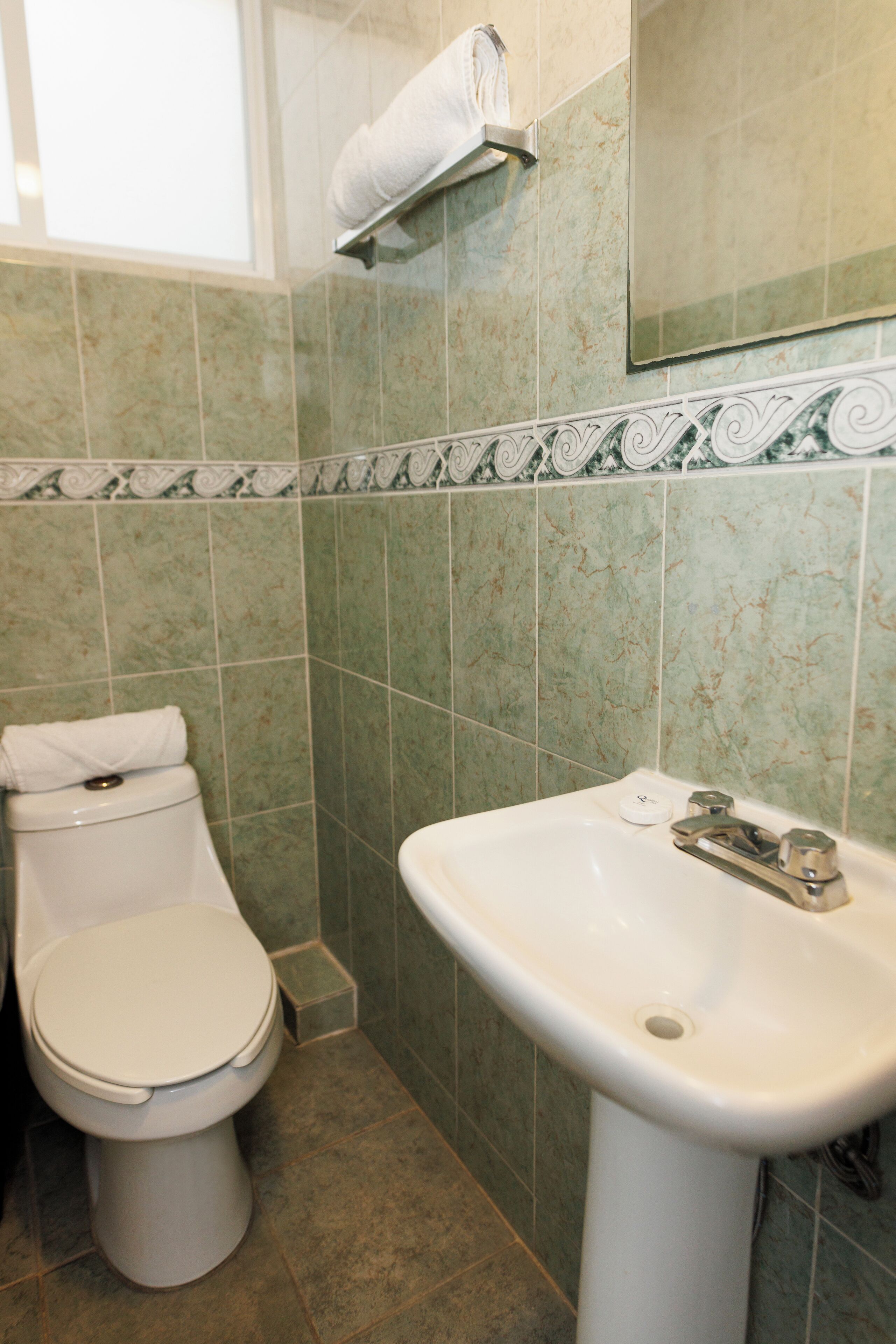 Ein Badezimmer mit Toilette, Waschbecken und Handtuchhalter.