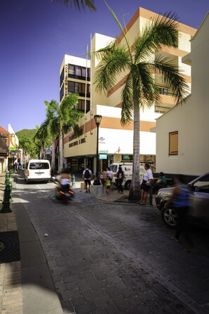 A street with buildings, palm trees, and a white van. - Horizon View Beach Hotel (Philipsburg)