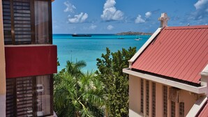 A view of a coastal area with a large ship in the water, a small boat, and a building with a red roof. - Horizon View Beach Hotel (Philipsburg)