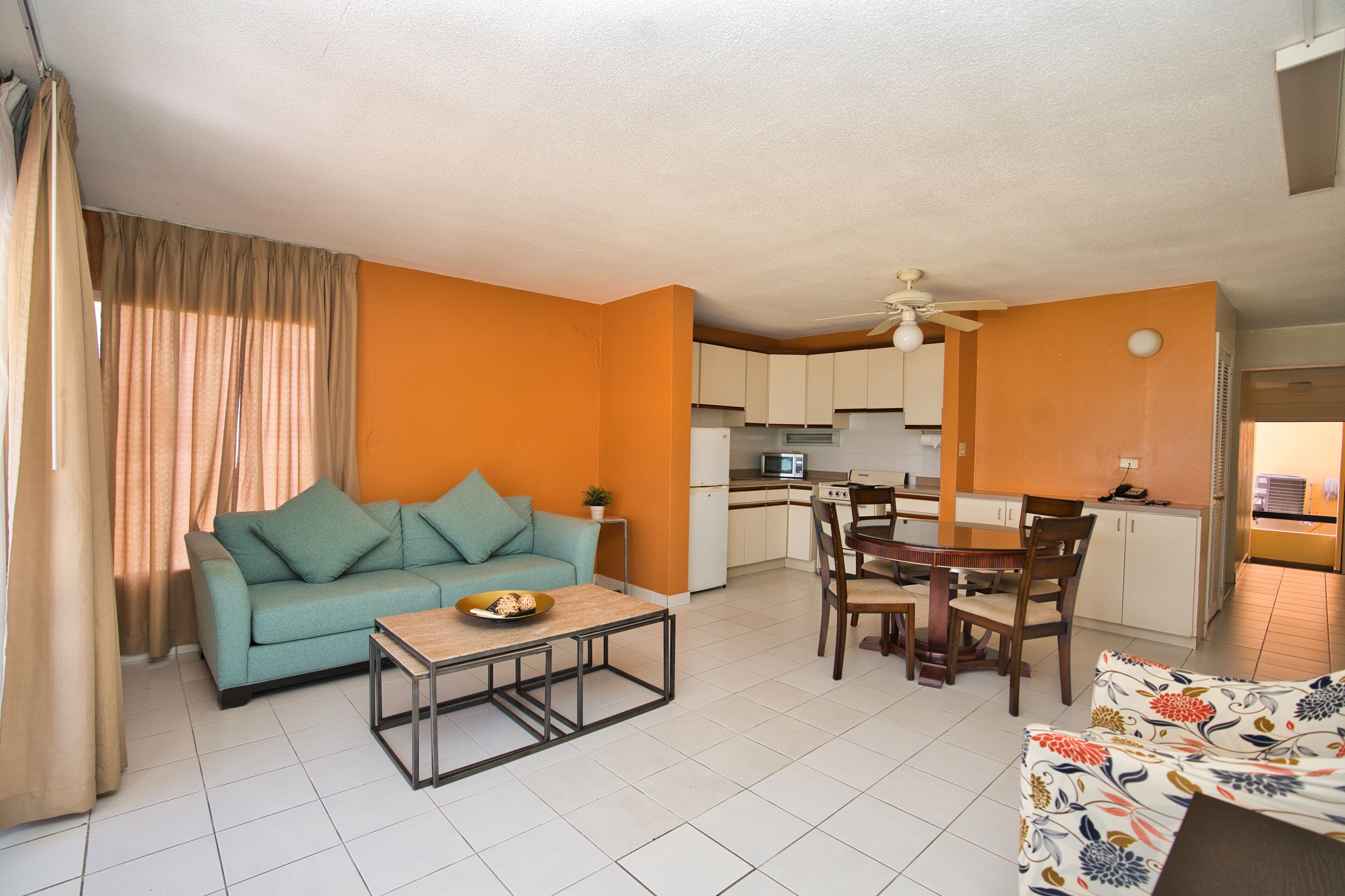 A living room with a sofa, coffee table, and dining area with chairs and a table.
