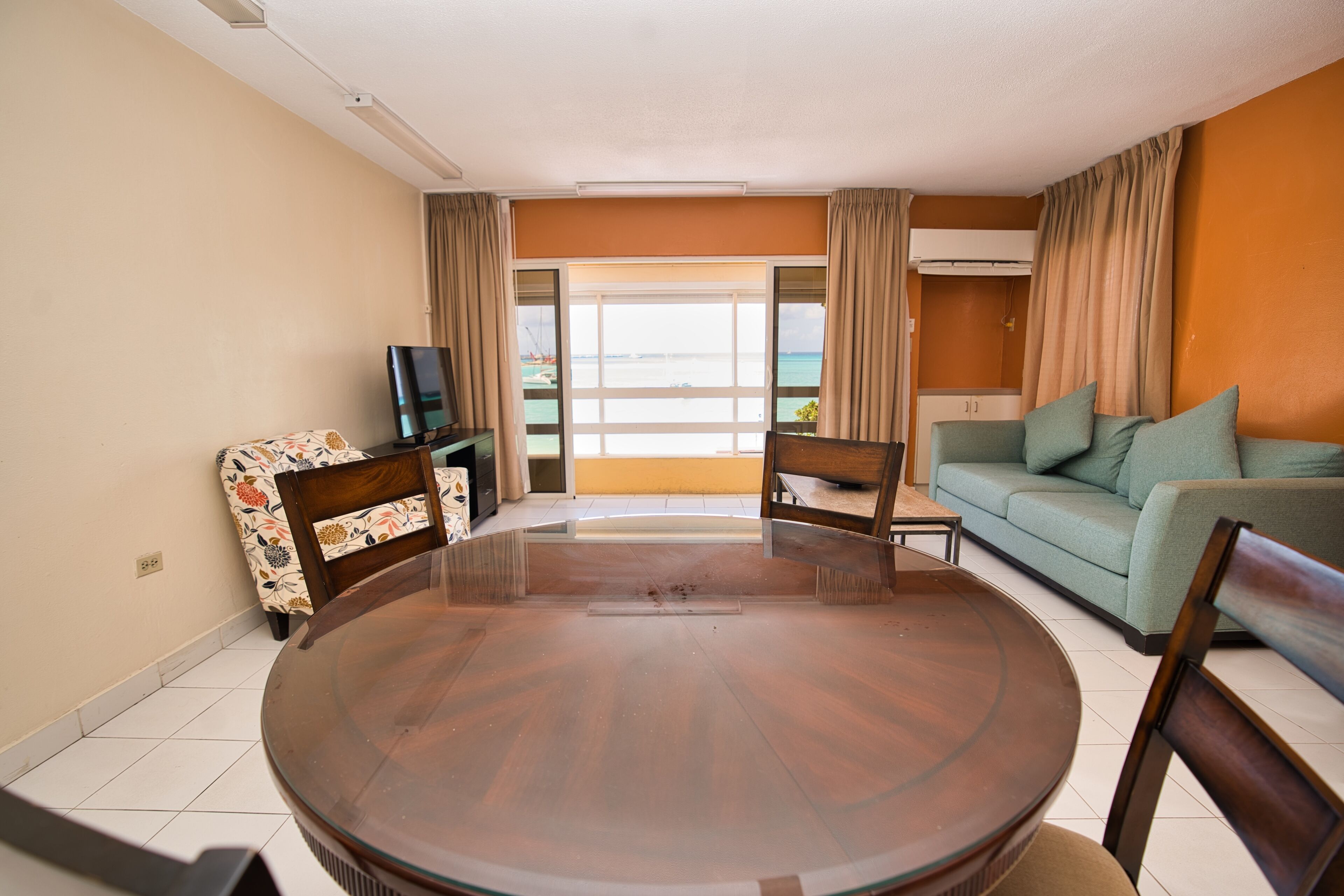 A living room with a round glass table, a sofa, and a television.