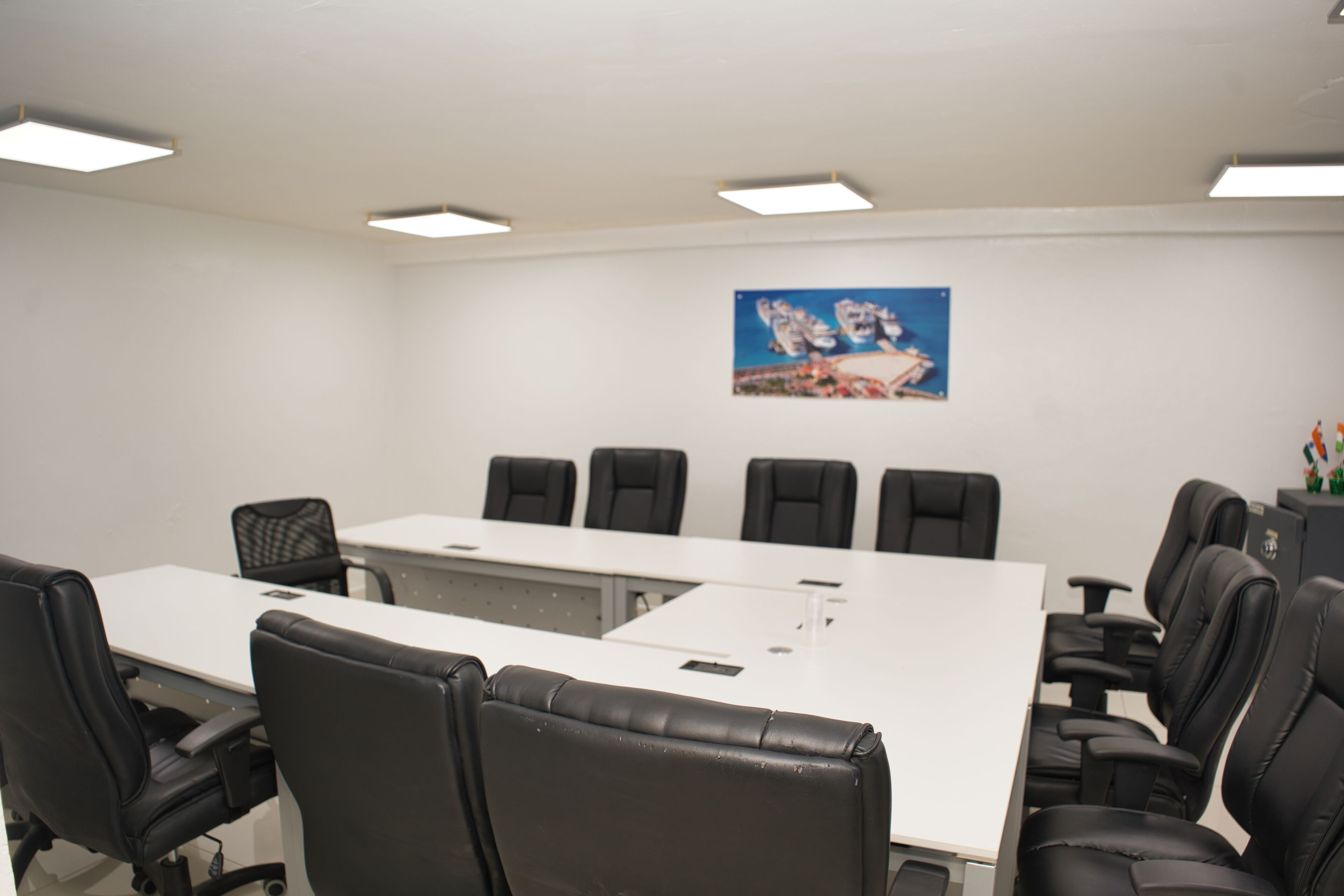 A conference room with a long table, black chairs, and a painting on the wall.