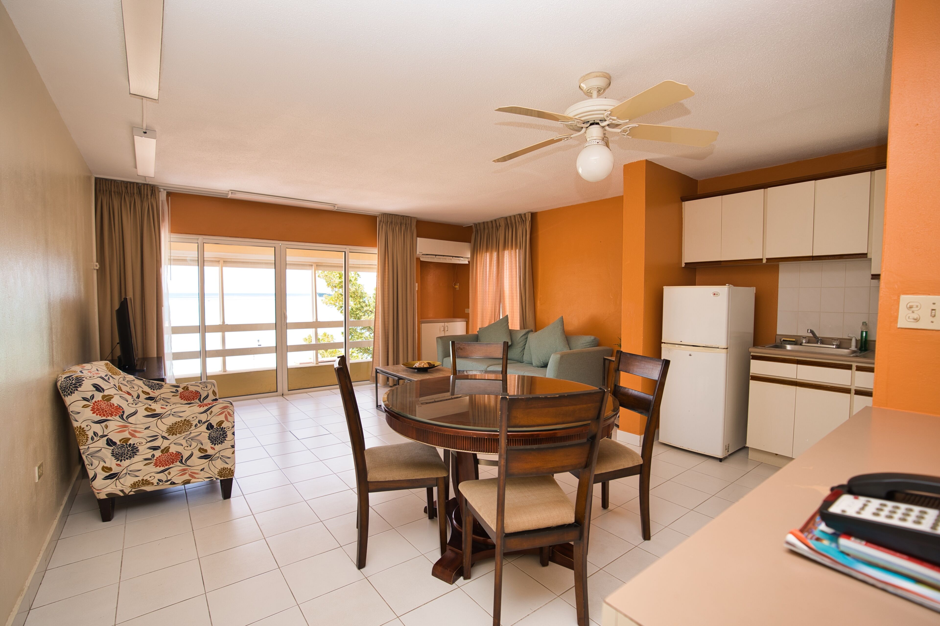 A compact living space with a dining area, a sofa, a kitchen, and a ceiling fan.