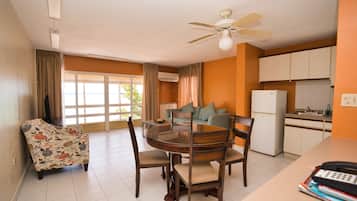 A compact living space with a dining area, a sofa, a kitchen, and a ceiling fan.