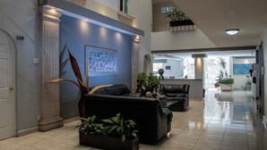A spacious lobby with a high ceiling, a reception desk, and a seating area with sofas and potted plants. - Hotel Qualitel Plus (Morelia)