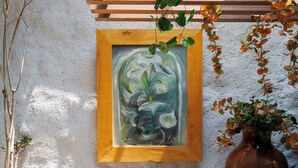A dining area with a wooden table, metal chairs, a potted plant, a large vase, and a framed painting on the wall. - Hotel Qualitel Plus (Morelia)