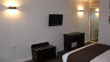 Habitación de hotel con cama, televisor montado en la pared, escritorio pequeño y espejo.