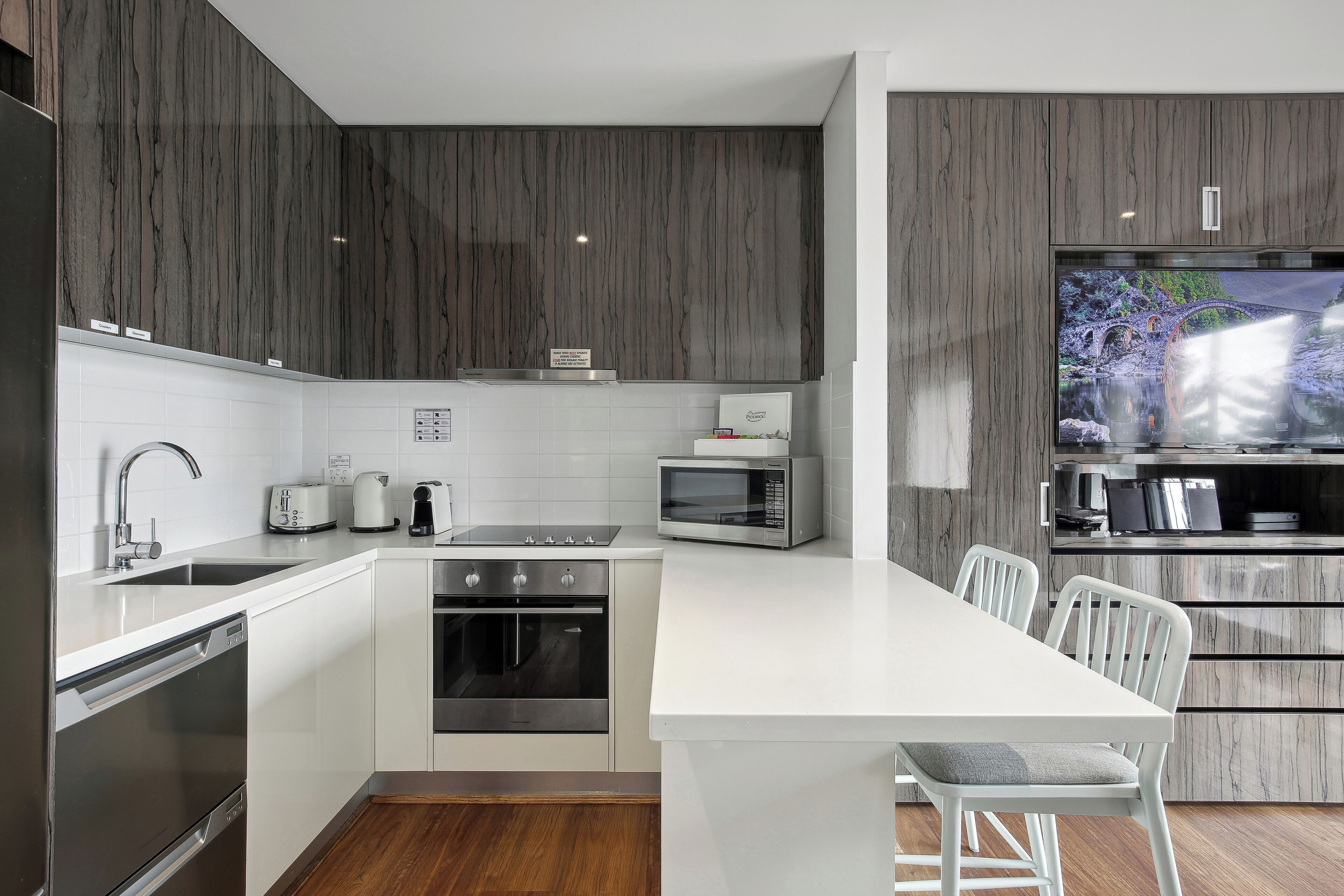 A modern kitchen with white cabinetry, stainless steel appliances, and a large island with bar stools.