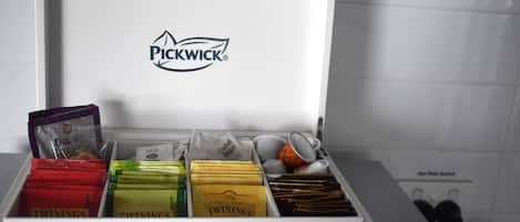 Una scatola portaoggetti bianca con scomparti che contengono diversi oggetti, incluso il logo Pickwick visibile sul coperchio.