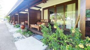 Un espacio al aire libre techado con mobiliario de madera y plantas en macetas.