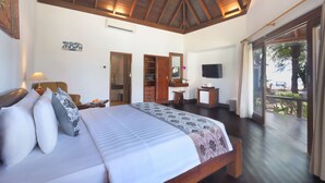 Un dormitorio con una cama grande, vigas de madera en el techo, televisión y un balcón con vistas al exterior.