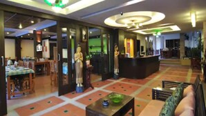 A hotel lobby with a reception desk, a statue, a dining area, and a patterned floor. - MT Hotel Patong (Patong)