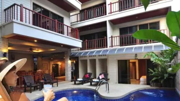 A hotel with a pool area, outdoor seating, and a multi-story building with balconies. - MT Hotel Patong (Patong)