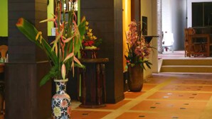 A hotel lobby with a tiled floor, a reception desk, and potted plants. - MT Hotel Patong (Patong)