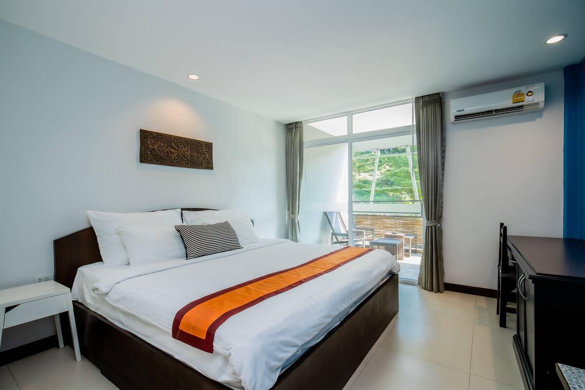 Habitación de hotel con una cama grande, un escritorio y vistas al exterior.