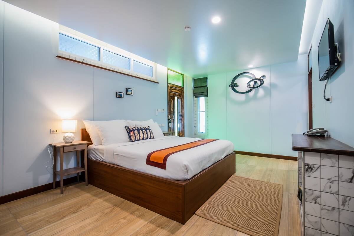 Un dormitorio con cama de madera, mesita de noche y un escritorio con silla.