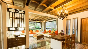 A spacious living area with a wooden ceiling, a dining table, and a sofa with colorful cushions. - Kata Tranquil Villa (Karon)