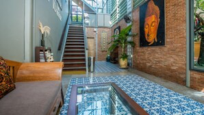 A spacious lobby with a staircase, a Buddha painting, and a large potted plant. - Kata Tranquil Villa (Karon)