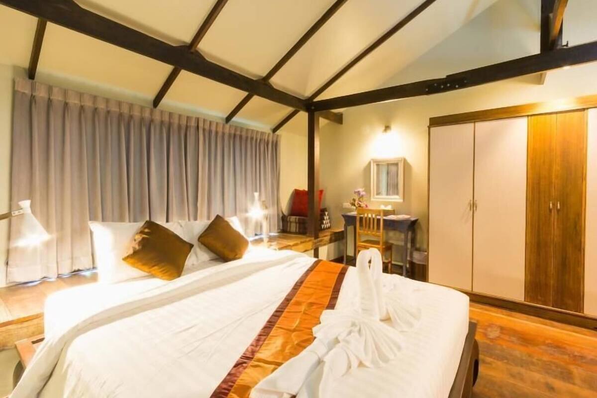 Habitación de hotel con una cama grande, un escritorio, un armario y una ventana con cortinas.