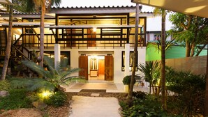 A two-story building with a covered outdoor area, a staircase, and a pathway leading to the entrance. - Kata Tranquil Villa (Karon)