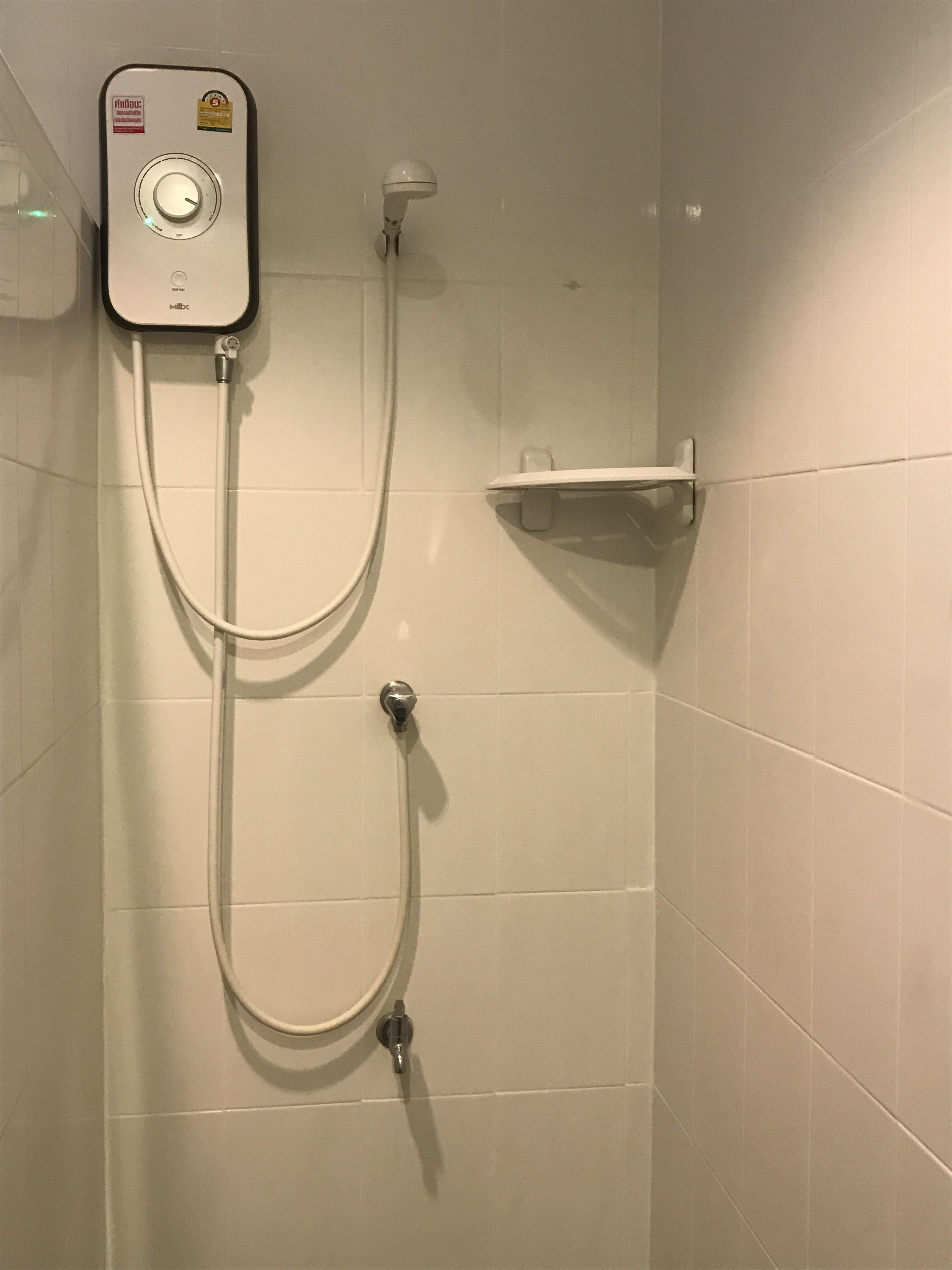 En bruser med kontrolpanel, håndbruser og vægmonteret hylde.