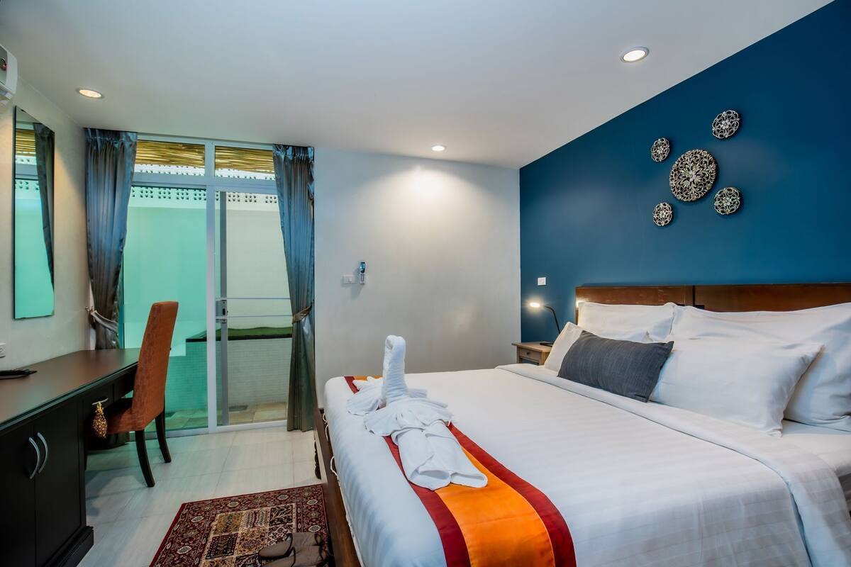Habitación de hotel con cama, escritorio, silla, zona de ducha y decoración mural.