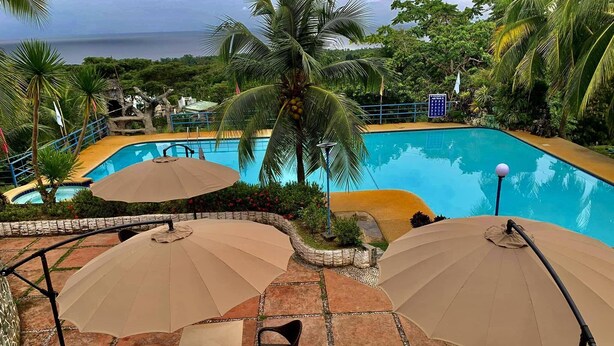 A poolside area with umbrellas, chairs, and a view of the sea.